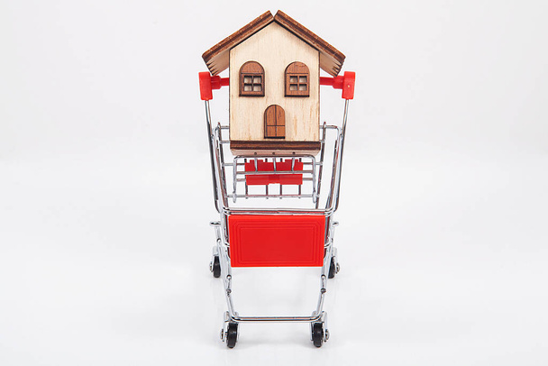 Concepto de agente inmobiliario. Modelo de casa dentro del carrito de compras. - Foto, Imagen
