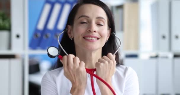 Mulher médico inserindo estetoscópio em seus ouvidos na clínica 4k filme câmera lenta - Filmagem, Vídeo