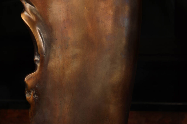 Een stukje gepolijst bronzen beeldhouwwerk met een scherpe rand aan de linkerkant - Foto, afbeelding