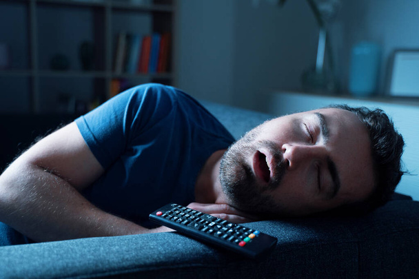 One guy sleeping on the sofa at night watching tv - Fotó, kép