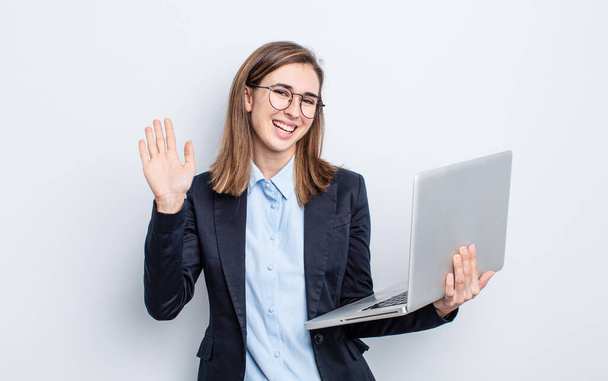 businesswoman young pretty woman smiling happily, waving hand, welcoming and greeting you. business and laptop concept - Foto, afbeelding