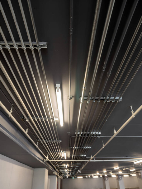 Instalación ordenada de tubos metálicos eléctricos galvanizados (EMT) Conductos en el techo del edificio de estacionamiento - Foto, Imagen