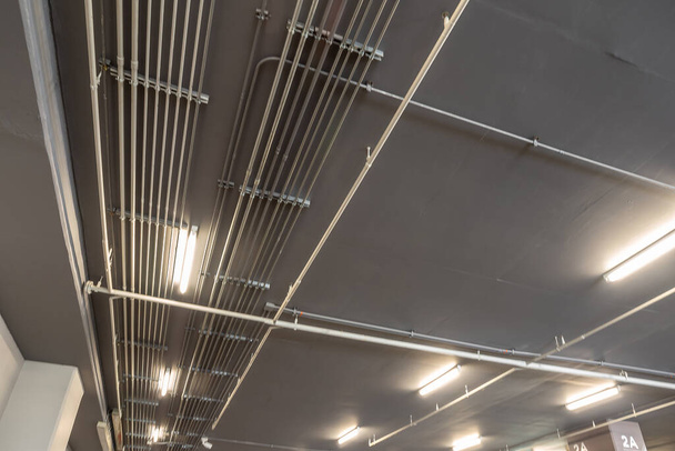 Tidy installation of Galvanized Electrical Metallic Tubing (EMT) Conduits on the ceiling of parking building - Fotografie, Obrázek