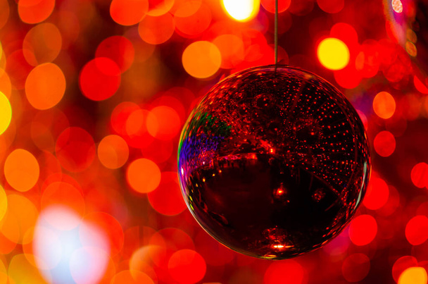 Красная безделушка висит, чтобы украсить для рождественского праздника с красочными боке от света и других безделушек. - Фото, изображение