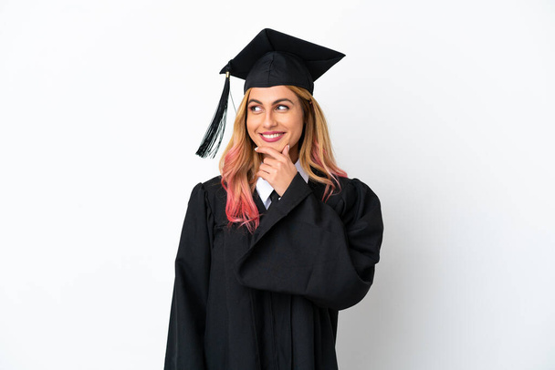 Young university graduate over isolated white background looking to the side and smiling - 写真・画像