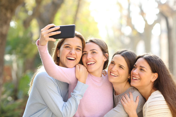 Four happy friends taking selfies with smart phone in the street - Foto, Imagem