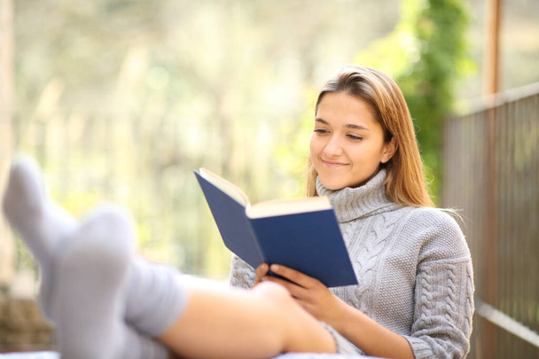 Satisfied woman relaxing reading a book in a terrace - Foto, Imagen