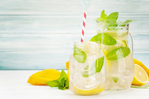 Fresh homemade lemonade with lemon and mint in pitcher and glass jar - Фото, зображення