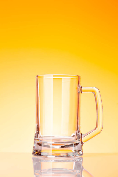 Empty glass beer in front of yellow background. Studio shot - Zdjęcie, obraz