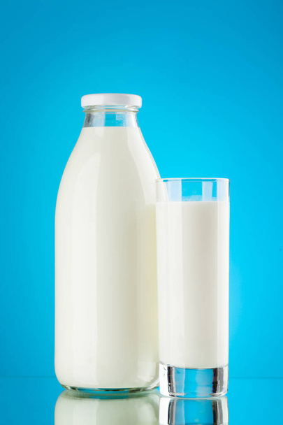 Milchflasche und Glas auf blauem Hintergrund. Milchprodukte - Foto, Bild