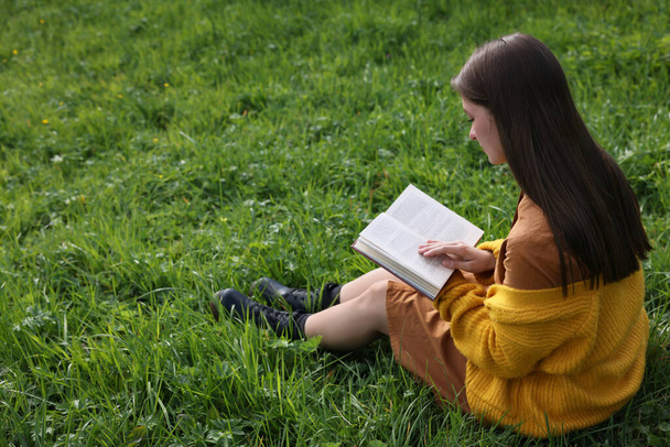 Young woman reading book on green grass - Fotoğraf, Görsel
