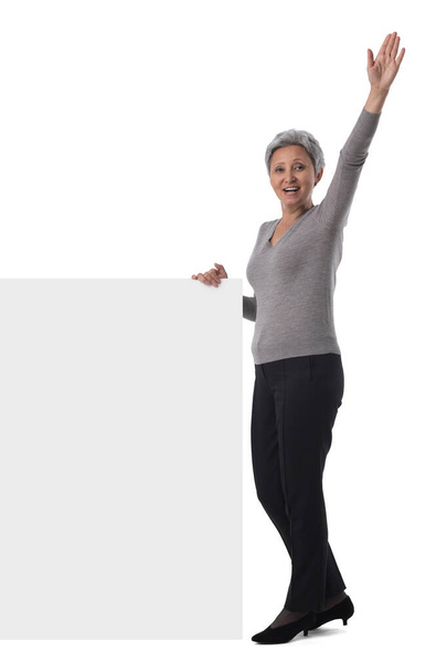 Mature asian business woman is holding empty text sign over white background - Zdjęcie, obraz