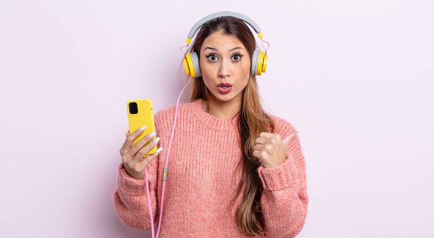 asiatic pretty woman looking astonished in disbelief. headphones and phone concept - Photo, image