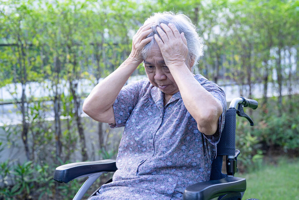 Asiatische Seniorin oder ältere Dame Patientin Kopfschmerzen, wenn sie auf dem Bett in der Krankenstation sitzt, gesundes starkes medizinisches Konzept  - Foto, Bild