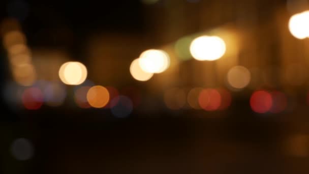 Όμορφη λαμπερή bokeh σε σκούρο θολή φόντο τη νύχτα. Το στρογγυλό πολύχρωμο bokeh λάμψη από τα φώτα των αυτοκινήτων στο δρόμο της πόλης. Εκτός εστίασης με θολή εικόνα. Μη εστιασμένα φώτα της πόλης. Κυκλοφορίας bokeh. Περίληψη - Πλάνα, βίντεο