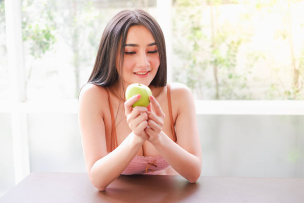 Porträt sexy asiatische Frau trägt Dessous oder Unterwäsche mit grünem Apfel in der Hand, gesundes Ernährungskonzept - Foto, Bild