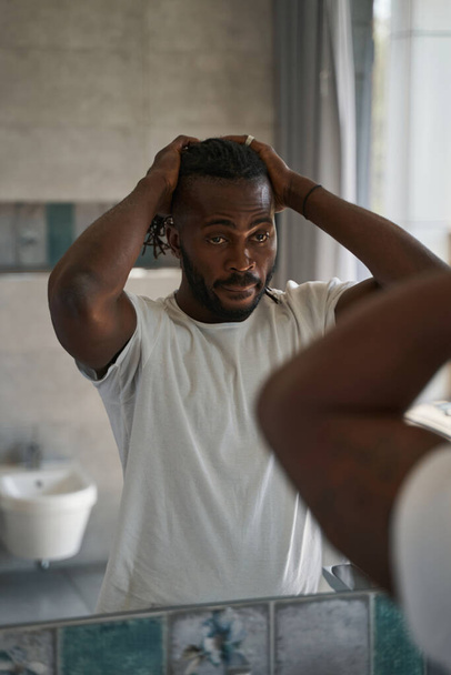 Serious focused African American guy standing in bathroom - Foto, Imagem