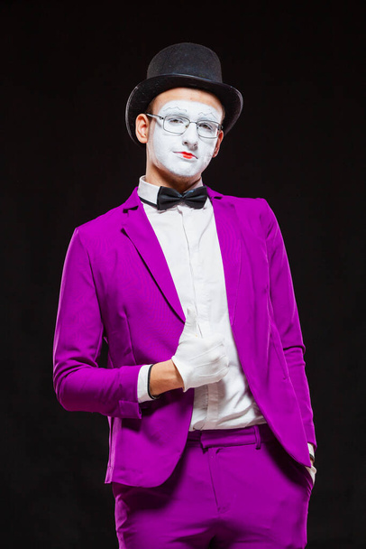 Portrait of male mime artist, isolated on black background. Man in purple suit shows thumb up and smiles. Symbol of self confidence, victorious, good result - Фото, изображение