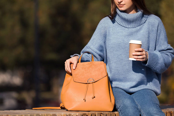 Young woman with stylish backpack and hot drink on autumn day, closeup. Space for text - Zdjęcie, obraz