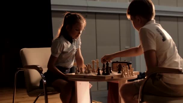 Αγόρι και κορίτσι παίζουν σκάκι σε ένα μικρό τραπέζι σε ένα όμορφο δωμάτιο. - Πλάνα, βίντεο