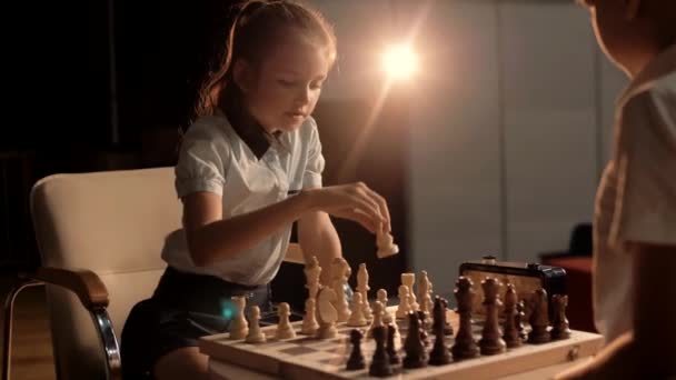 Ein nettes junges Mädchen macht während eines Wettbewerbs einen verantwortungsvollen Schachzug mit einer Schachfigur - Filmmaterial, Video