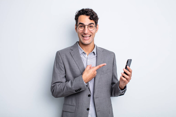 hispanic handsome man looking excited and surprised pointing to the side. business and phone concept - Photo, image