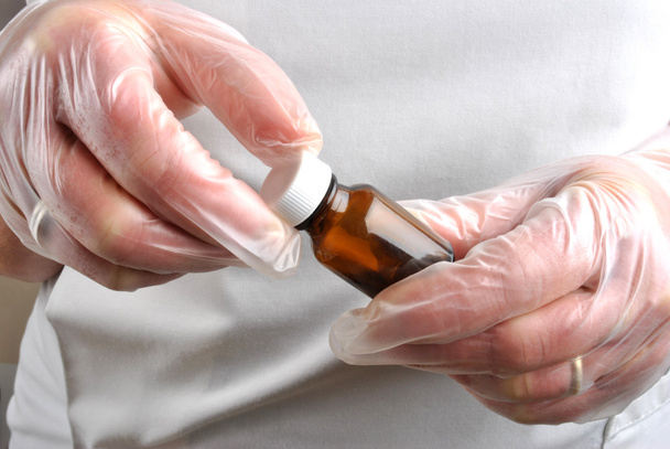 gezondheidszorg personeel met wegwerp handschoen open pil fles - Foto, afbeelding