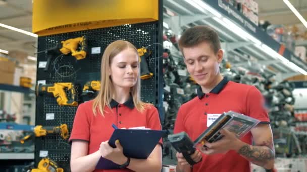 Młodych konsultantów sprzedaży facet i dziewczyna w pracy w dużym supermarkecie materiałów budowlanych - Materiał filmowy, wideo