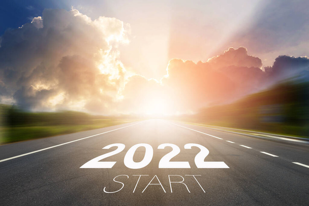 Start to New year 2022 concept. Start 2022 written on highway road in the middle of empty asphalt road with sunset or sunrise light above asphalt road - Photo, Image
