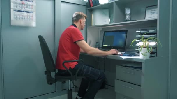 DIY materiali da costruzione direttore dell'azienda lavora il telefono con i clienti in un cubicolo ufficio di fronte al suo computer - Filmati, video