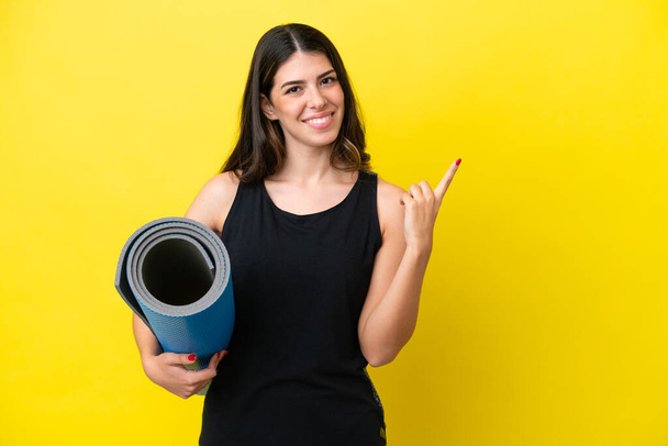 sport Italian woman going to yoga classes isolated on yellow background pointing to the side to present a product - Photo, Image