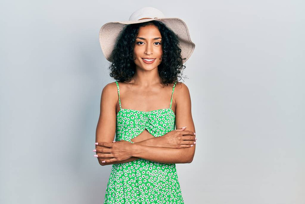 Joven chica latina con sombrero de verano cara feliz sonriendo con los brazos cruzados mirando a la cámara. persona positiva.  - Foto, Imagen