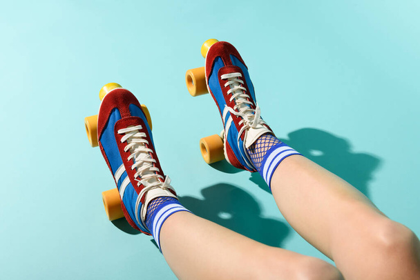 From above of crop anonymous female in bright colorful socks and roller skates resting in sunlight against blue background - Фото, зображення