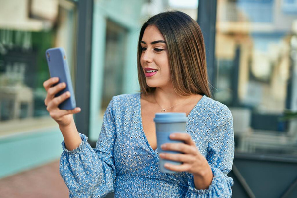 Young hispanic woman smiling happy using smartphone at the city - Photo, Image