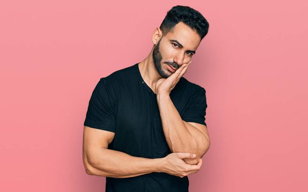 Hispanic man with beard wearing casual black t shirt thinking looking tired and bored with depression problems with crossed arms.  - Foto, Bild