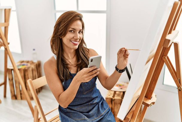 Junge hispanische Künstlerin Frau lächelt glücklich Zeichnung im Kunstatelier. - Foto, Bild