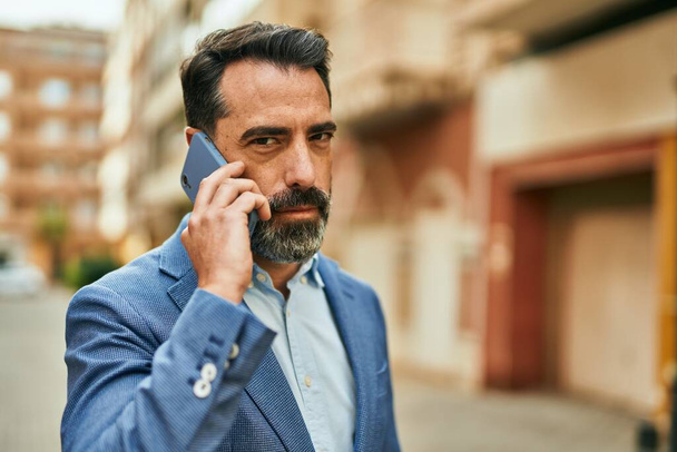 Бізнесмен середнього віку з серйозним висловлюванням на смартфоні в місті
. - Фото, зображення
