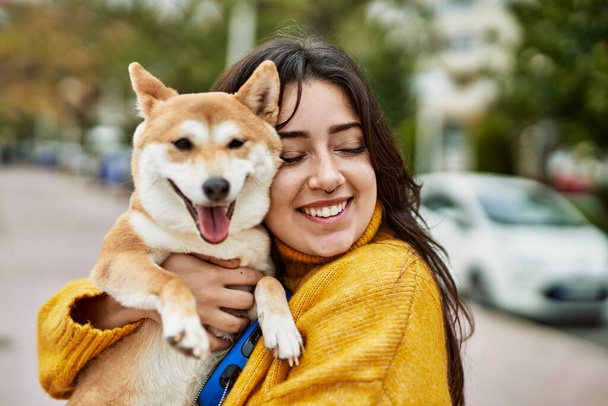 Piękna młoda kobieta przytula szczęśliwego psa shiba inu na ulicy - Zdjęcie, obraz