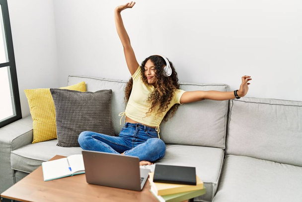 Giovane donna latina stanco stretching braccia utilizzando il computer portatile a casa - Foto, immagini