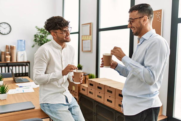 Двоє іспаномовних бізнесменів п'ють каву, працюючи в офісі
 - Фото, зображення