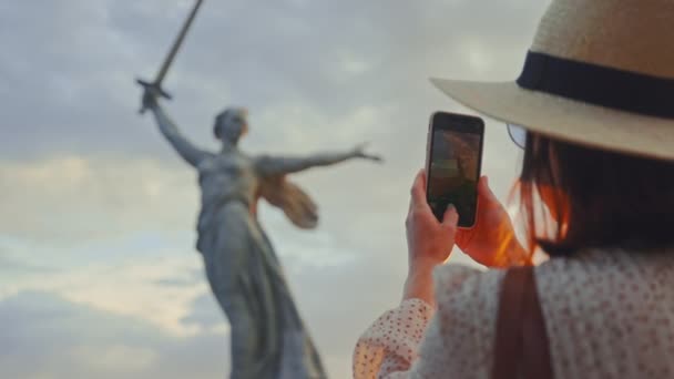 A young tourist in a hat taking a photo of the Motherland on a smartphone - Footage, Video