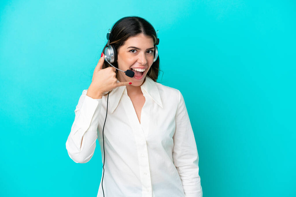 Telemarketer Italian woman working with a headset isolated on blue background making phone gesture. Call me back sign - Photo, Image