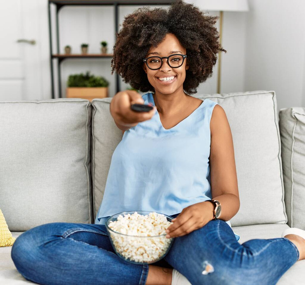 Genç Afro-Amerikan kadın gülümsüyor. Evde film izlerken kendine güveniyor. - Fotoğraf, Görsel