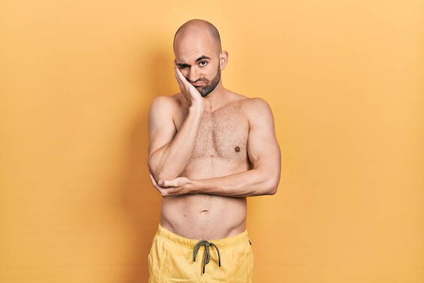 Young bald man wearing swimwear thinking looking tired and bored with depression problems with crossed arms.  - Foto, Bild