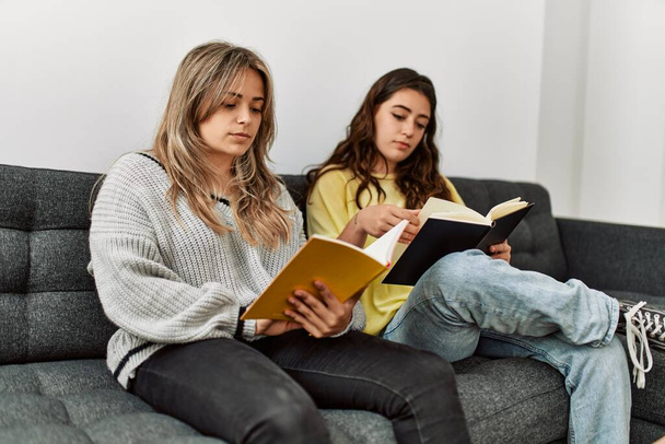 Mladý pár čtení kniha sedí na pohovce doma. - Fotografie, Obrázek