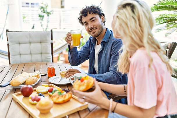 Young couple smiling happy having breakfast sitting on the table at terrace. - 写真・画像