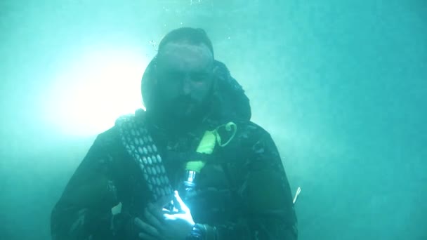 De man in militaire uitrusting opent zijn ogen onder water, close-up. Portret - Video