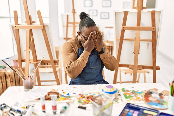 African american artist man at art studio with sad expression covering face with hands while crying. depression concept.  - Fotografie, Obrázek