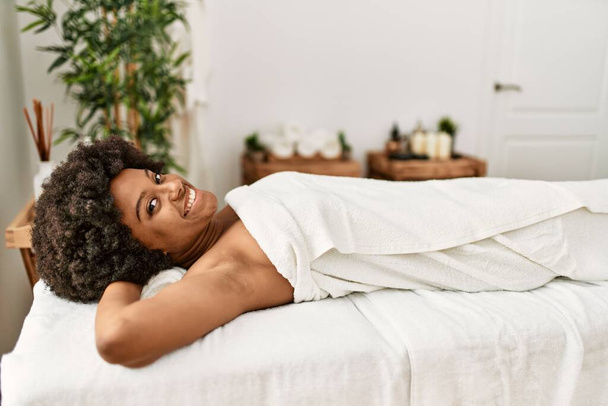 Young african american woman smiling confident lying on massage table at beauty center - Foto, Imagem