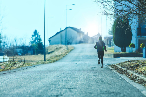 Tanınmayan bir kadın şehrin sokaklarında koşuyor, hava soğuk ama gerçekle yüzleşip formda kalıyor. - Fotoğraf, Görsel